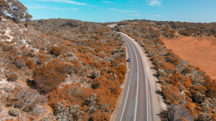 Road crossing beautiful countryside on a sunny day. Overhead downward aerial view from drone perspective