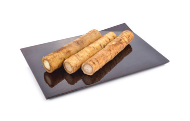 fresh burdock root or Gobo on black plate with white background