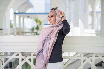 Close up portrait of happy young Asian woman wearing hijab, Islamic stylish modern fashion, smiling and posing at Shah Alam Mosque.