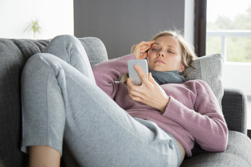 Sick woman with scarf around neck, texting on mobile