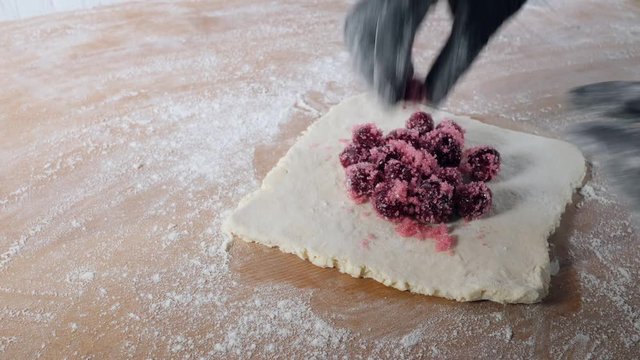 Chef hands work with dough prepares sweet pastries with berries