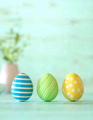Three colorful Easter eggs on green wood