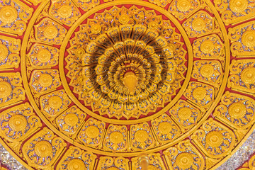 Beautiful golden decorated ceiling in lotus shape with lamp at the Buddhist church, Thailand.