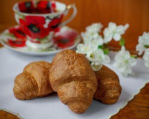 Croissants decorated with spring flowers. A cup of tea. Close-up. Spring.	