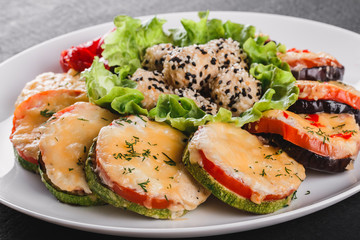 Healthy appetizer, grilled zucchini and eggplant with cheese with cheese on plate over black stone background. Clean eating, vegan food concept. Top view, flat lay