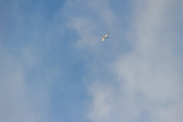Fototapeta na wymiar Faraway flying airplane against blue sky and white cloud background.