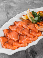 Seafood platter with salmon slice, shrimp, slices fish fillet, decorated with olives and lemon in plate over rustic background. Mediterranean appetizers