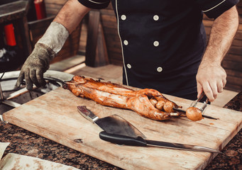 Chef Hands cutting grilled rabbit for steaks with knife on cutting board. Hot Meat dishes