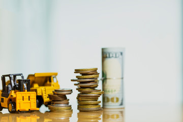 Financial And Macro Economic Concept, pile of coins money stacked on wooden table, with construction vehicle and equipment. Vintage tone.