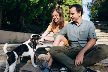 Beautiful cute couple is sitting in the city with their dog jack russel terrier. Beautiful young woman and handsome man are having fun outdoors with jack russel terrier.