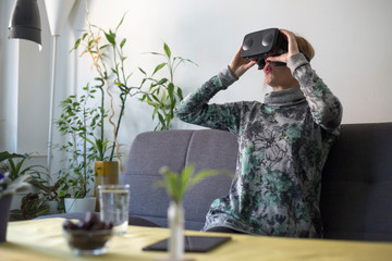 woman at home enjoying virtual reality goggles on sofa