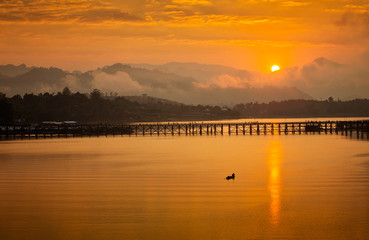 Golden morning light. Mon Bridge is the long wooden bridge. Official name is Attanusorn Bridge. Is the route of the villagers cross to Mon village, Sangkhla Buri, Kanchanaburi, Thailand 24 Jan 2019
