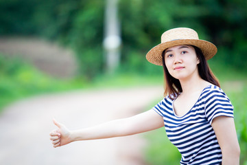 Alone Asian women calling for help beside the road and showing thumb up sign.
