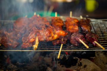 Chicken BBQ grilling on wood fire close up.