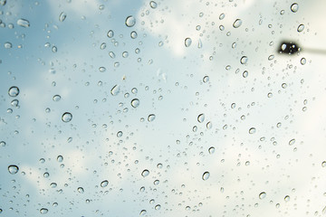 Rain drop on window glass with sky in background close up.