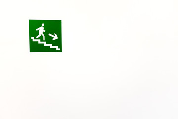 Green sign down the stairs on an empty bright wall