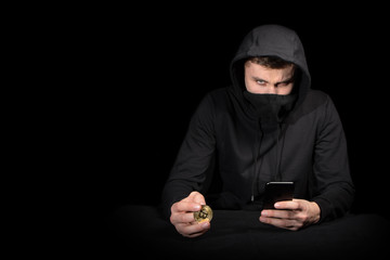 Hacker with mobile phone and bitcoin initiating cyber attack, isolated on black