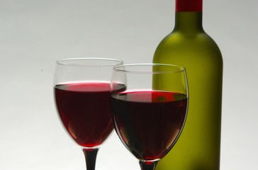 Two glasses of red wine and two bottles.