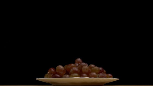 Plate with rotating frozen grapes, close-up, slow motion, copy space