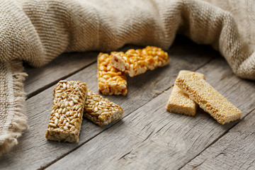 Assorted kozinaki, on old vintage background, with burlap fabric. Country style. Delicious sweets from the seeds of sunflower, sesame and peanuts, covered with shiny glaze.