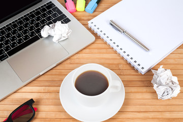 Business creativity concept. Laptop, sheets of paper and crumpled wads on table.