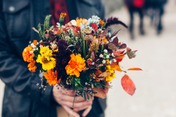 Wedding bouquet in a bright autumn style in the hands of the groom. Marigold flowers