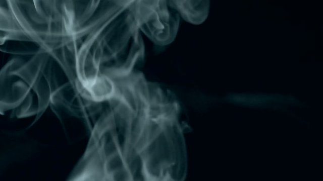 White smoke slowly rising graceful twists on black background blowing from bottom to top. Slow motion,