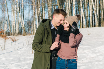 Beautiful young couple in love walks and laughs in a park on a clear sunny winter day.