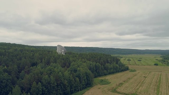 Aerial view radio telescope in forest. Drone flight around satelite antenna