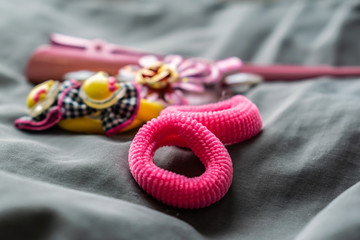 Children's jewelry set of pink rubber bands and hairpins with pendants in the form of cat faces. Cute and beautiful set for girls on grey background. Flowers and beads. Bright color. New jewelry.