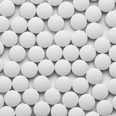 Small white pills on a white background close-up.