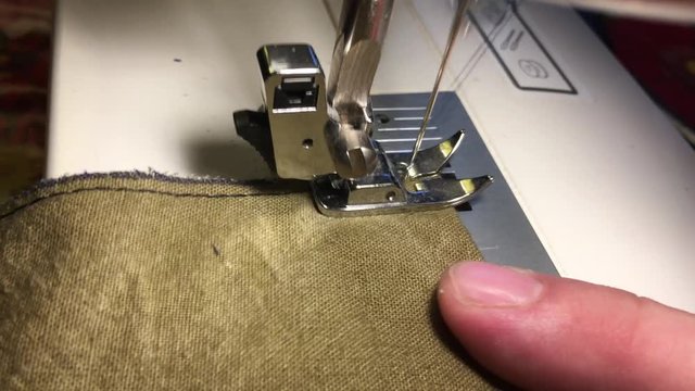 Fabrics on the sewing machine. The needle scribbles a thread on the rough fabric. 
