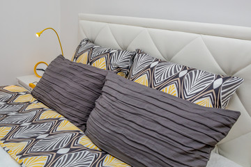Close up of modern decorative pillows at double bed. Modern hotel bedroom interior.