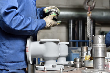 The base for the valve is mounted on an iron table for assembly at the factory and the worker installs and fastens the components.