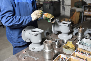 The base for the valve is mounted on an iron table for assembly at the factory and the worker installs and fastens the components.