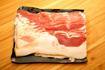 Packaged Raw Bacon on a Wooden Cutting Board