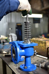 The base for the valve is mounted on an iron table for assembly at the factory and the worker installs and fastens the components.