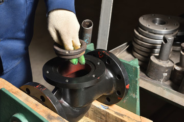 The base for the valve is installed and clamped in a vice for assembly at the factory and the worker installs and fastens the components.