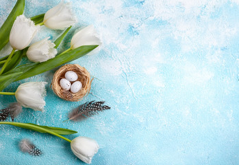 Easter composition with Easter eggs in nest and white tulips