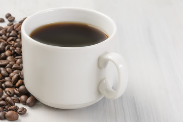 a cup of black natural coffee, coffee beans, on a light wooden table
