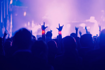 Concert, event or party concept. People with hands up near the scene, spotlight, colored blue light.