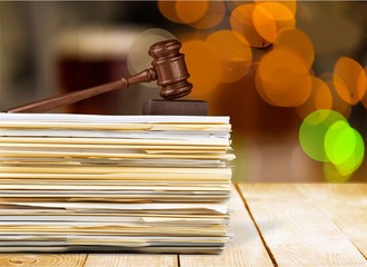 Judge hammer and documents on wooden table at blurred library background