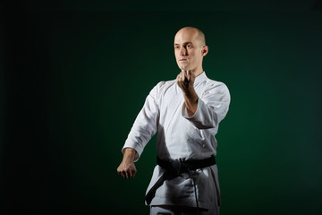 Active athlete performs formal karate exercises on a dark green background