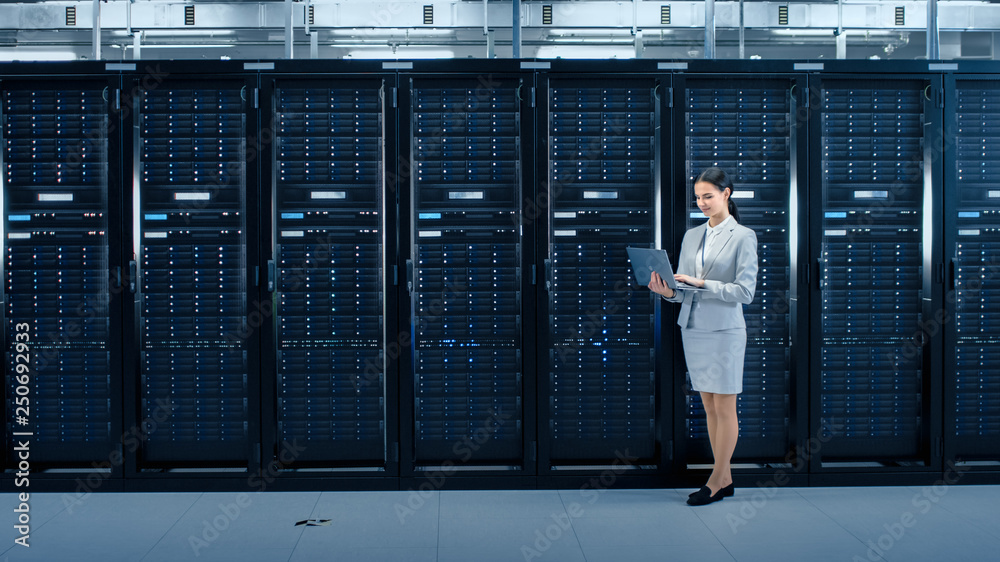 Leinwandbilder female data center it engineer works on laptop computer next to server rack corridor. running diagno