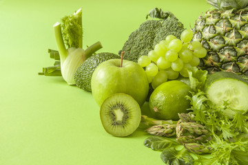 Green health smoothie fruits and vegetables, kale leaves, lime, apple, kiwi, grapes, banana, avocado, lettuce pineapple salat. Copy space. Raw, vegan, vegetarian, alkaline food concept.