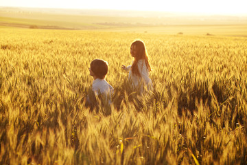 Happy mom and son run through a field of rye in the rays