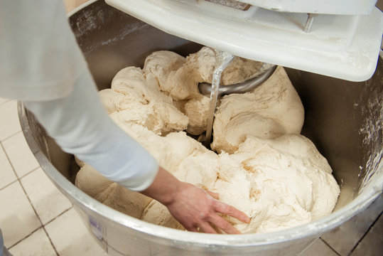 Baker preparing the dough for bread in a dough mixer