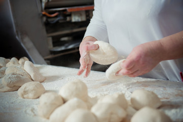 Woman baker make buns from dough
