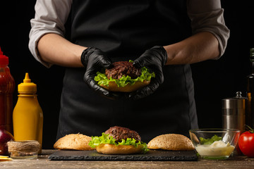 the chef prepares a burger, a hamburger. on a background with ingredients. Delicious and fast food, fast food