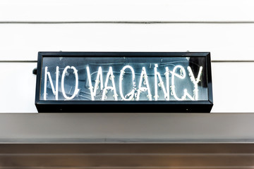 Closeup of electric neon No Vacancy sign on hotel exterior during day